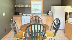 Une cuisine équipée d’une cuisinière, d’un évier et d’un réfrigérateur, avec des meubles de rangement en bois et une fenêtre.
