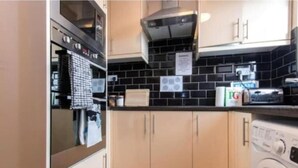 Eine kompakte Küche mit Waschmaschine, Mikrowelle und Toaster.