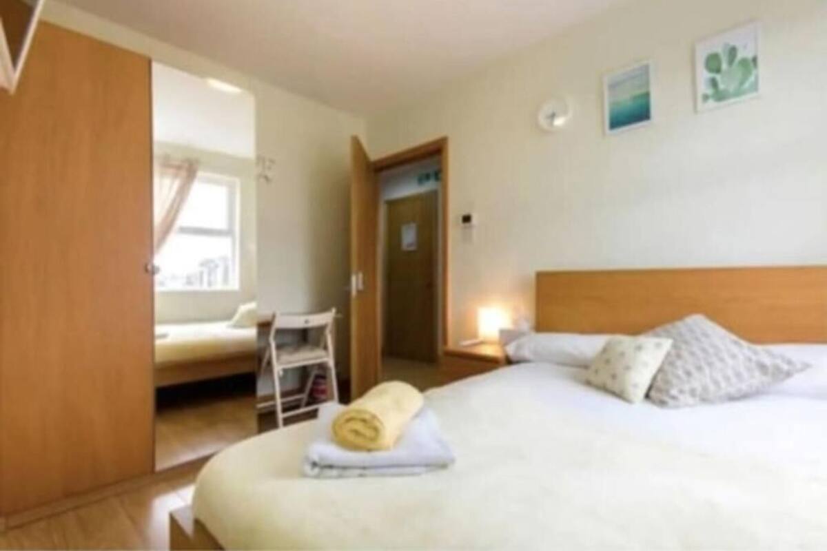 Une chambre d’hôtel comprenant un lit, une table de chevet, une commode, une armoire et une porte donnant sur une autre pièce.