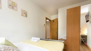 Ein Schlafzimmer mit einem Bett, einem Holzschrank, einem Spiegel und einem kleinen Tisch.