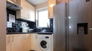 Eine kompakte Küche mit Waschmaschine, Kühlschrank und einem Fenster, das für natürliches Licht sorgt.