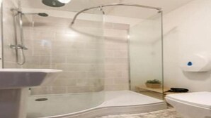 Ein modernes Badezimmer mit Duschkabine aus Glas, Waschbecken und Toilette.