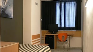 A small hotel room with a bed, a desk with a computer, a chair, and a window with curtains. - Hotel Nautico (Santa Cruz de Tenerife)