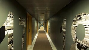 A hallway with a central carpeted walkway flanked by walls with mirrored panels reflecting construction images. - Hotel Nautico (Santa Cruz de Tenerife)