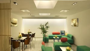 A modern interior with a dining area, green sofas, a coffee table, and a large plant. - Hotel Nautico (Santa Cruz de Tenerife)