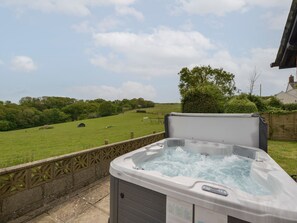 Un jacuzzi en un patio trasero con vista a un campo verde y árboles.