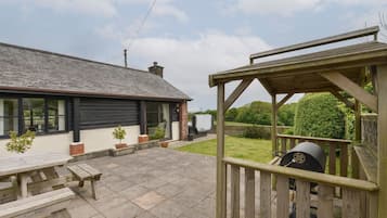 A house with a patio, a barbecue grill, and a wooden deck.