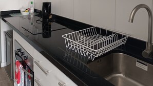 Une cuisine moderne avec des meubles blancs, un plan de travail noir, un évier en acier inoxydable et un égouttoir à vaisselle.