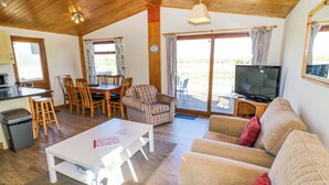A spacious living area with a sofa, a dining table, and a television. - Lavender Lodge (Evesham)