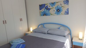 Une chambre à coucher avec un lit, deux lampes de chevet, un tableau de fleurs et une armoire.