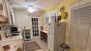 Cocina compacta con refrigerador, estufa y lavamanos. Cuenta con un pequeño comedor con una silla y una mesa.