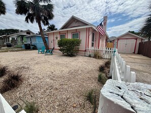 A residential area with houses, a gravel driveway, and a white picket fence. - Adorable 2-bedroom bungalow with AC in Daytona Beach, walking distance to beach (Daytona Beach)
