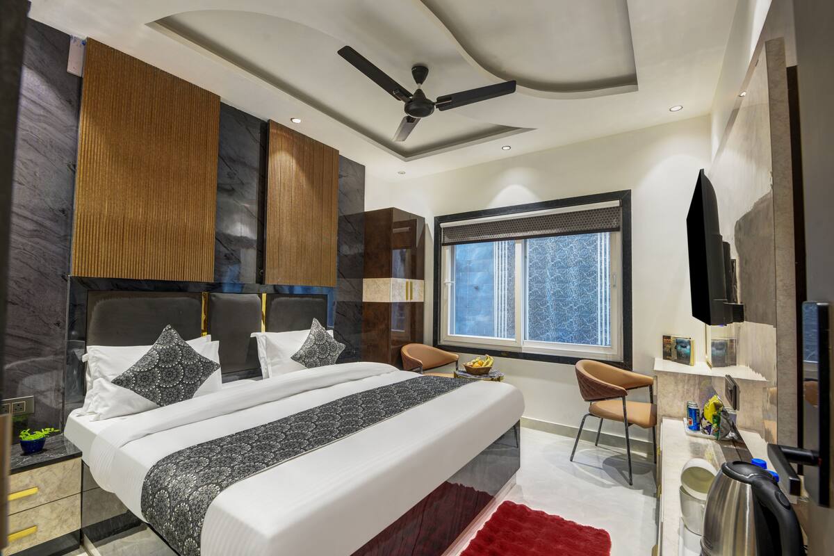 A modern bedroom with a bed, a desk, a chair, a window, and a ceiling fan.