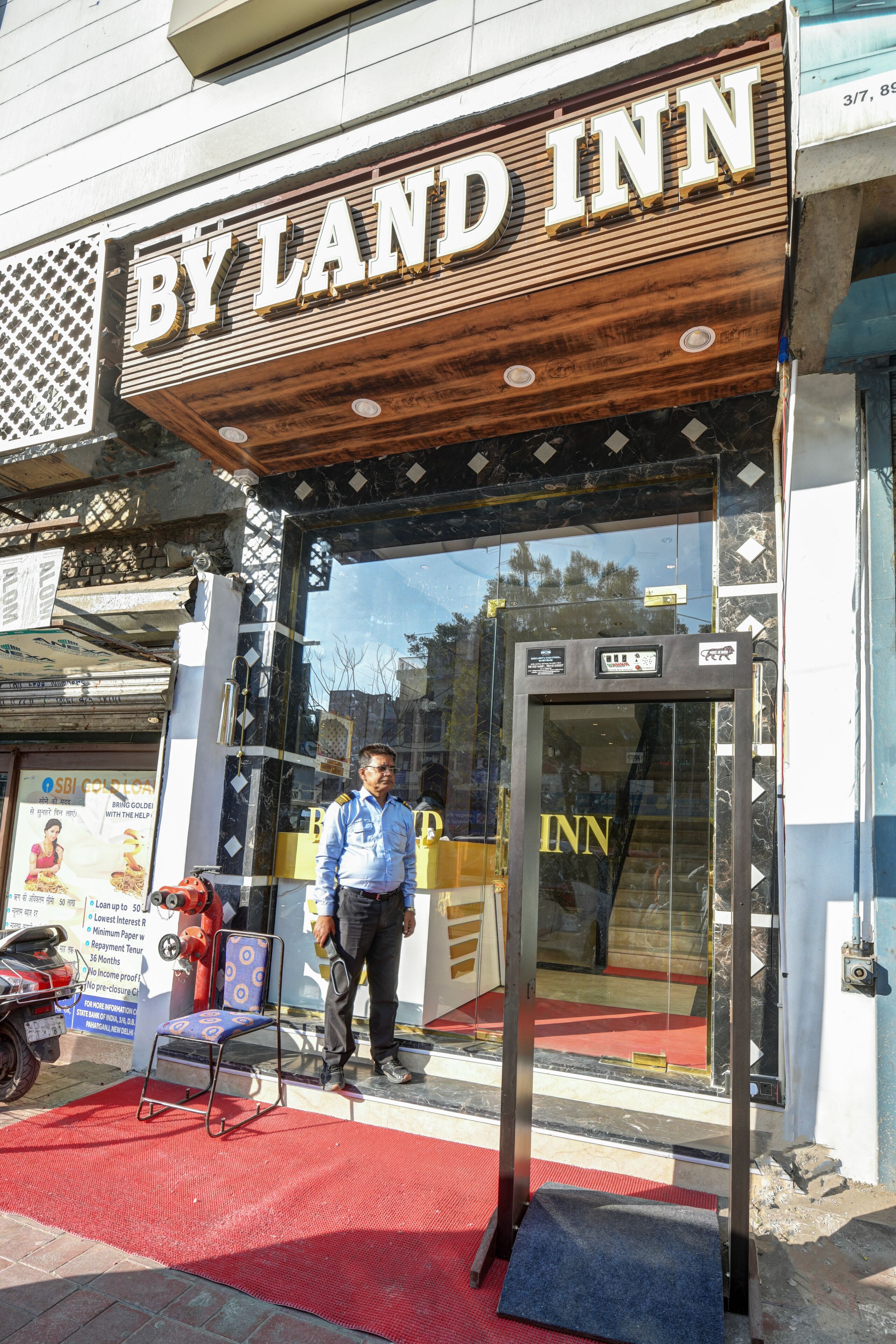 A hotel entrance with a wooden sign reading 'BY LAND INN' and a glass door.