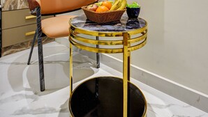 Un interior moderno con una pared de mármol, una mesa redonda con cesta de frutas, una silla y un espejo grande.