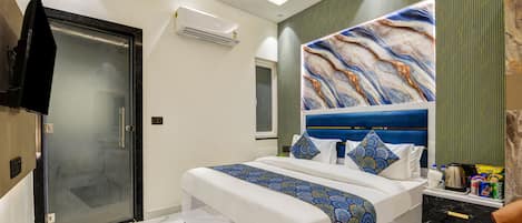 Ein modernes Schlafzimmer mit einem großen Bett, einer Duschkabine aus Glas, einem angebrachten Fernseher und einer Wanddekoration.