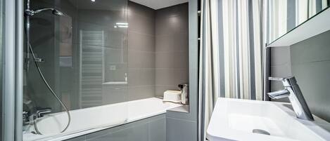 A modern bathroom with a glass-enclosed shower, a white sink, and a mirror.