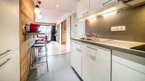 Una cocina moderna con armarios blancos, una campana de acero inoxidable y una lámpara colgante roja.