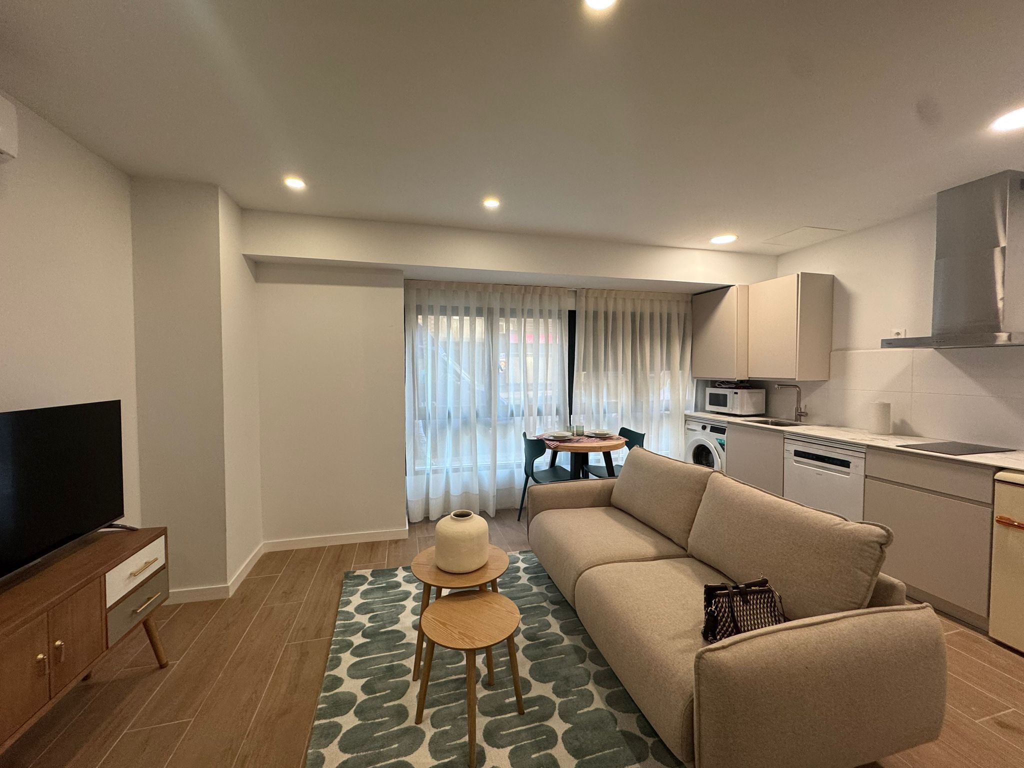 Un appartement moderne comprenant un canapé, un téléviseur, une table à manger et un coin cuisine.