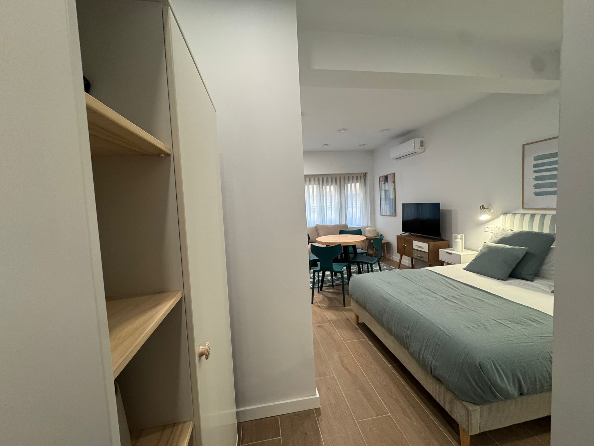 A bedroom with a bed, a desk, a chair, and a television.