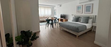 A modern bedroom with a large bed, bedside tables, a desk, and a chair.