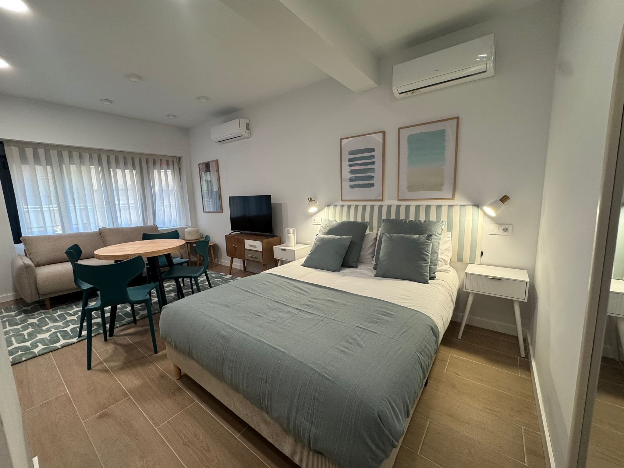 A modern hotel room with a bed, a TV, a desk, and a sofa.