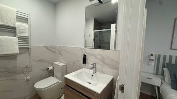 A modern bathroom with a toilet, sink, and mirror.
