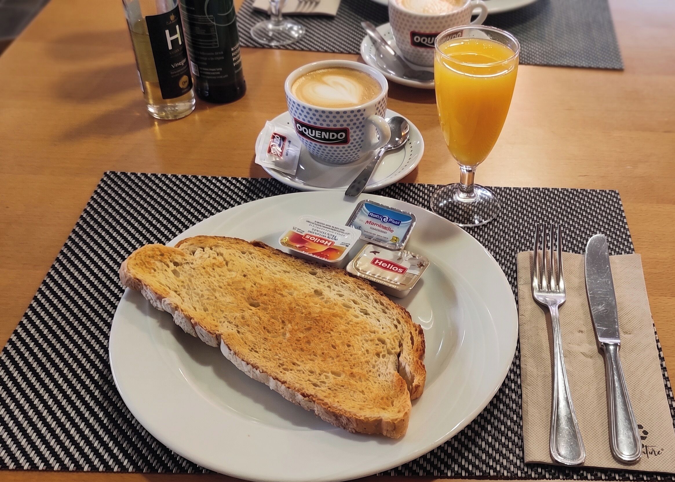 A breakfast setting with toast, coffee, orange juice, and condiments on a plate.