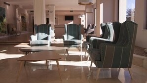 A modern hotel lobby with a seating area, large windows, and a flat-screen TV on the wall. - Hotel La Palma de Llanes by gaiarooms (Llanes)