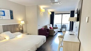 A hotel room with a bed, a desk, a chair, a sofa, and a balcony with a view. - Hotel La Palma de Llanes by gaiarooms (Llanes)