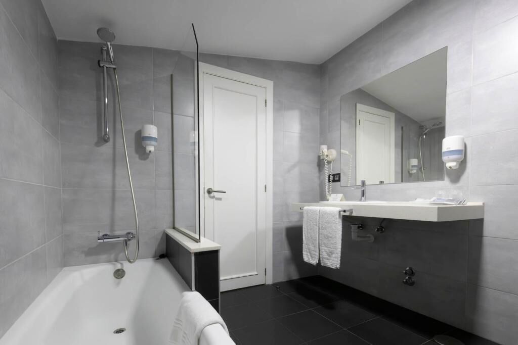 Un baño moderno con bañera, ducha, lavabo y espejo.