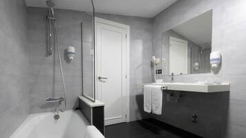 Un baño moderno con bañera, ducha, lavabo y espejo.