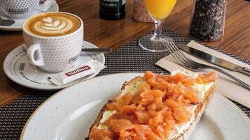 A breakfast setting with a sandwich, coffee, and juice on a table.