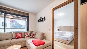 A modern room with a sofa, a small table, a bed, and a window with a mountain view.