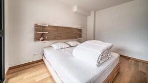 A bedroom with a bed, wooden slat headboard, white bedding, and a light fixture.