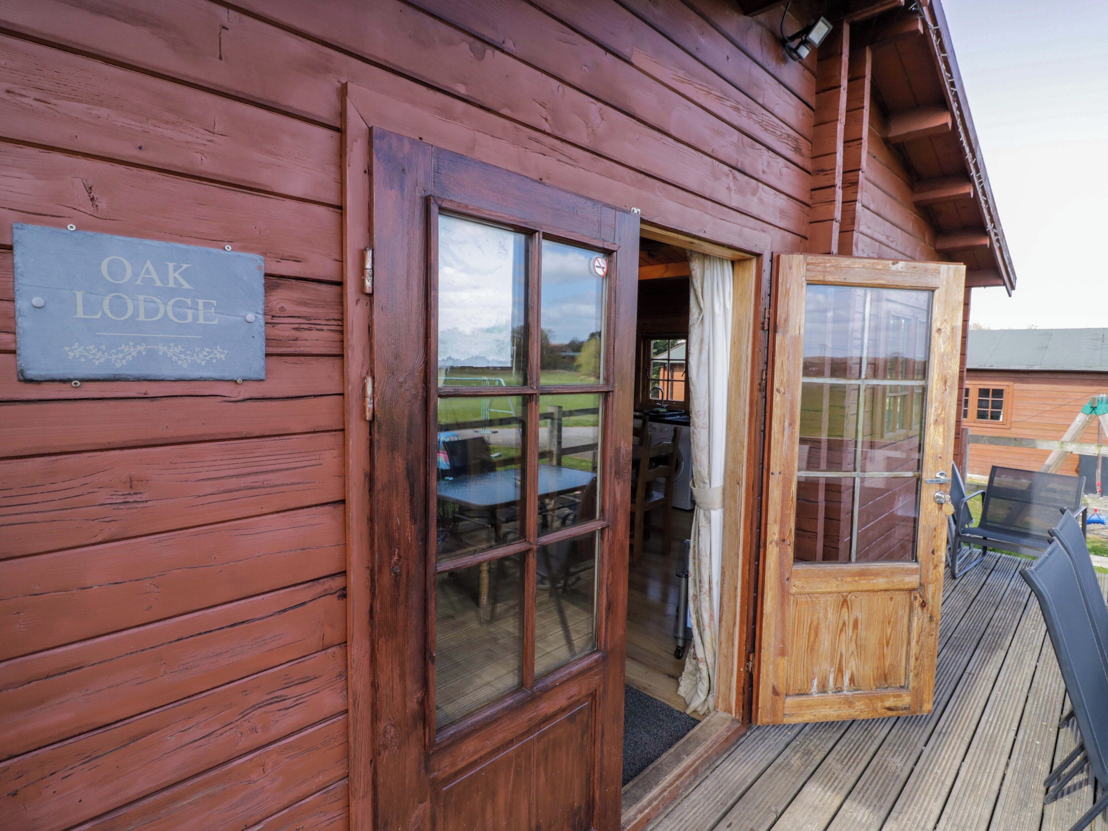 Een houten lodge met een bord waarop 'Oak Lodge' staat.
