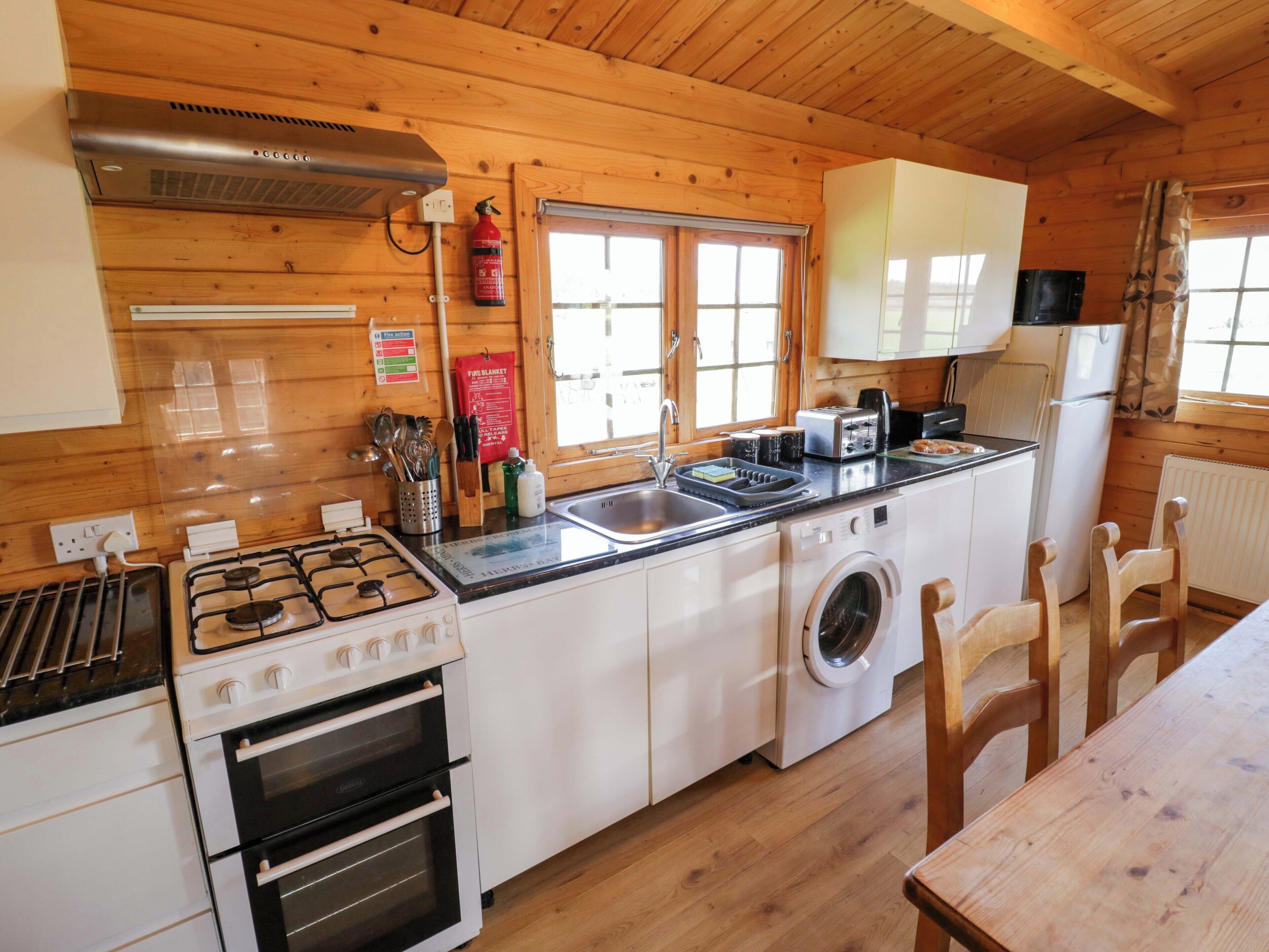 A kitchen with a stove, oven, washing machine, and a window with a view.