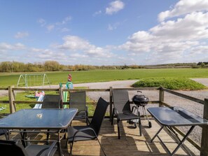 A deck with outdoor seating, a grill, and a swing set in the background. - Oak Lodge (Evesham)