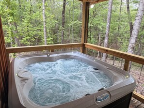 A hot tub with a wooden deck and a forest view. - Hot Tub Cabin Retreat • Near Montgomery & Troy, AL (Ramer)