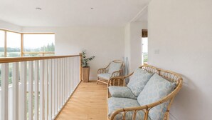 Ein Balkon mit Korbmöbeln, einer Topfpflanze und Blick ins Grüne.