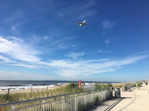 Un paseo marítimo con vistas al océano y un avión a reacción en el cielo.