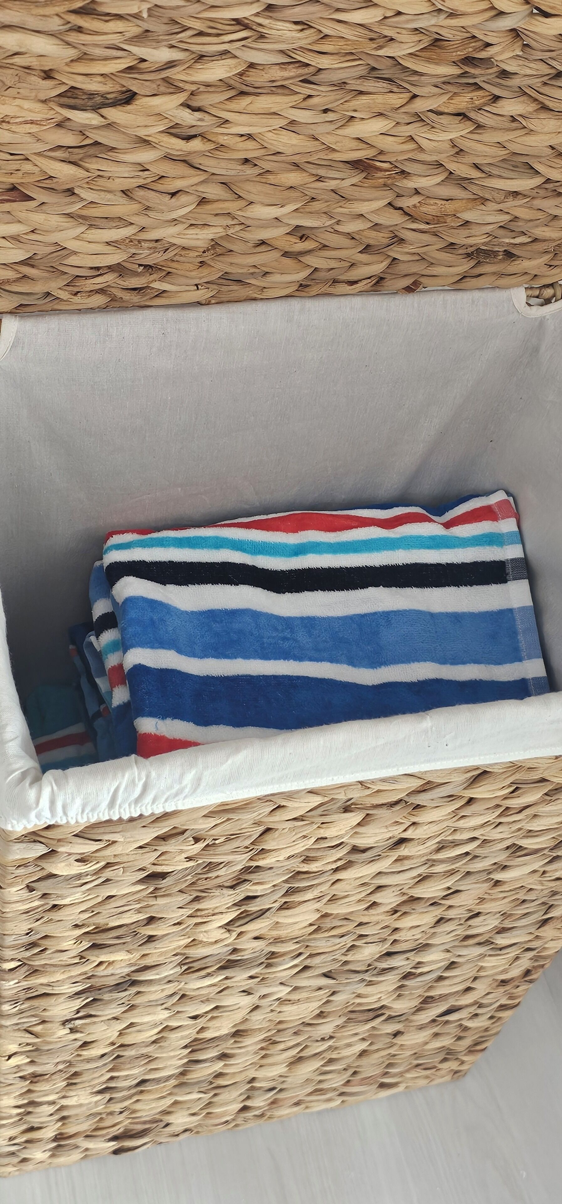 A woven basket with a striped towel inside.