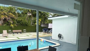 A poolside area with a table and chairs, a bench, and a fan.