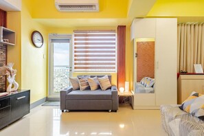 Comfort Condo, 1 Bedroom, Balcony, Pool View | Living room | 65-inch Smart TV with digital channels, books - Elevesuites Homestay (Quezon City)