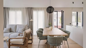 A modern living room with a sofa, dining table, chairs, and a hanging light fixture. - Líbere Porto Gaia (Vila Nova de Gaia)