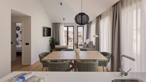 A modern dining area with a wooden table, wicker chairs, a vase, and a view of the city through large windows. - Líbere Porto Gaia (Vila Nova de Gaia)