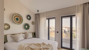 A bedroom with a large bed, a view through a sliding door, and decorative plates on the wall. - Líbere Porto Gaia (Vila Nova de Gaia)