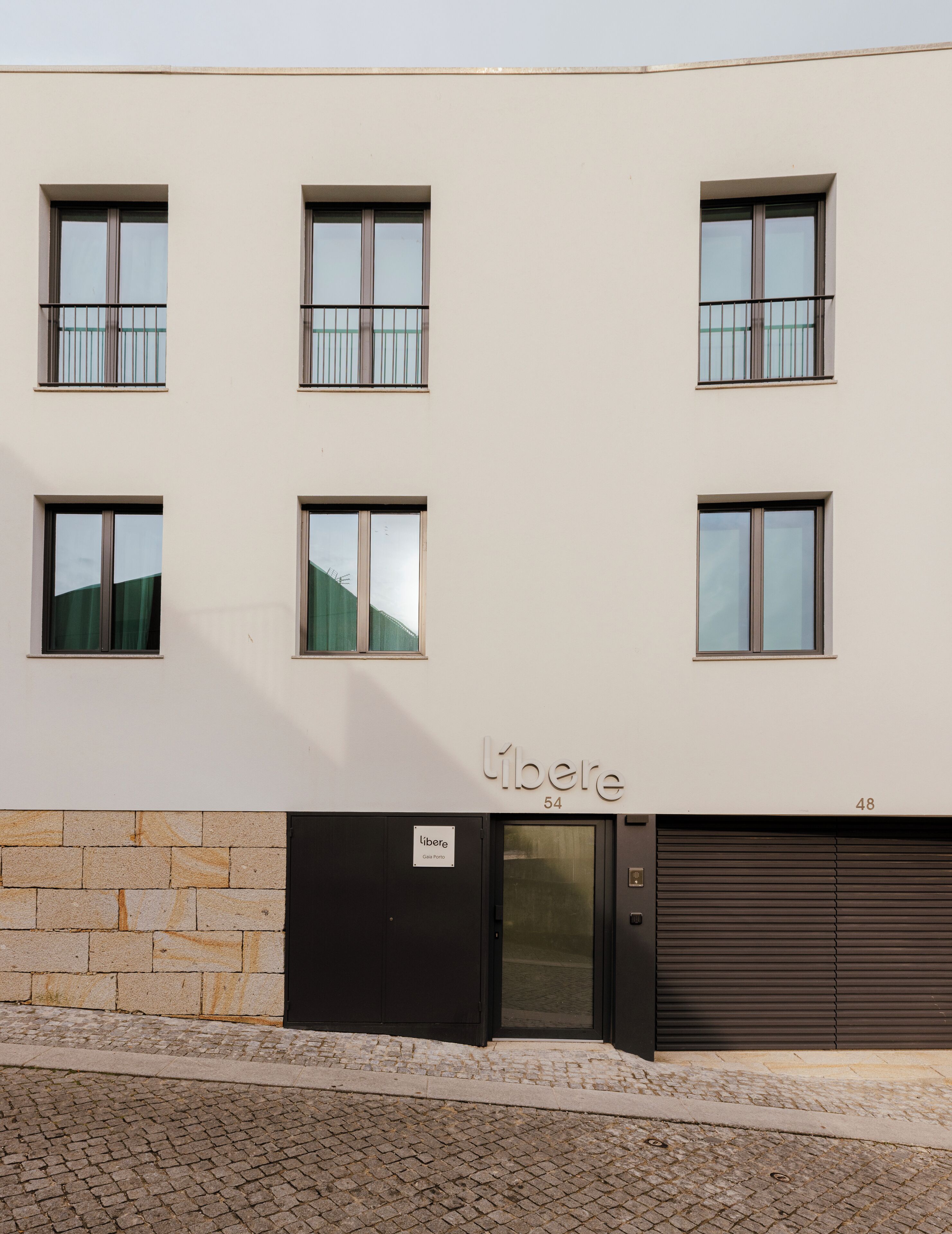 A modern building with multiple windows, a nameplate, and a garage door.