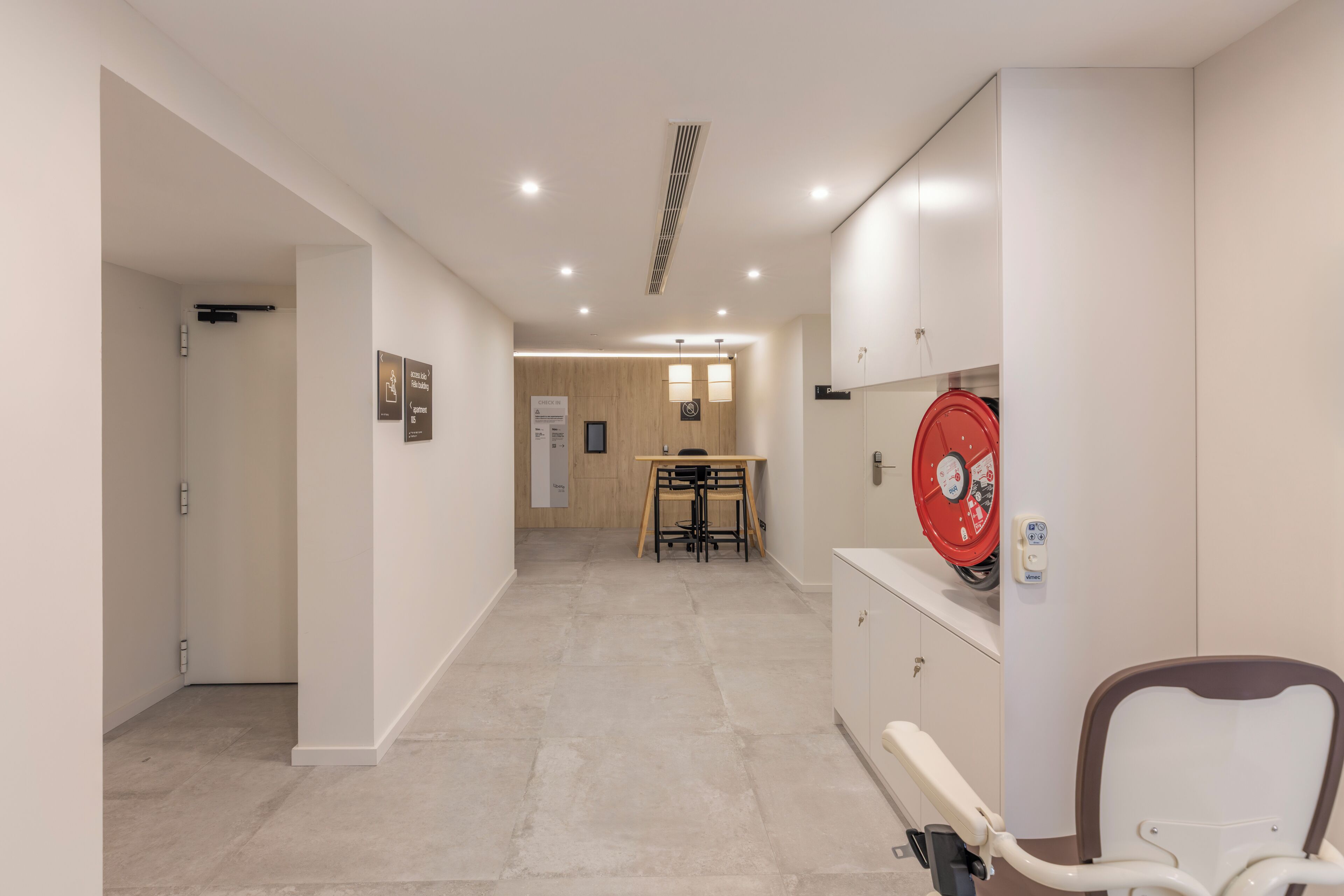 Un couloir avec un fauteuil de dentiste, une table et des chaises au fond.