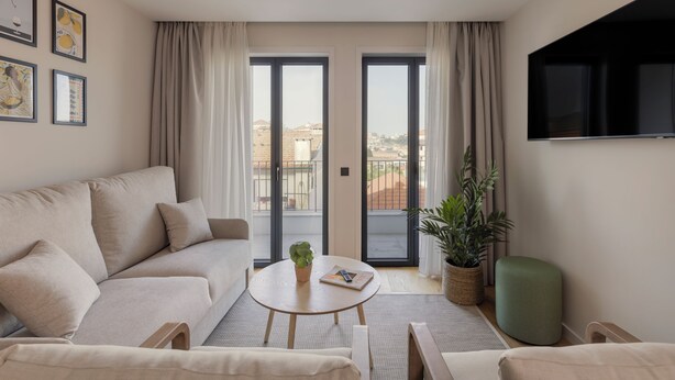 A modern living room with a sofa, a coffee table, and a TV. - Líbere Porto Gaia (Vila Nova de Gaia)